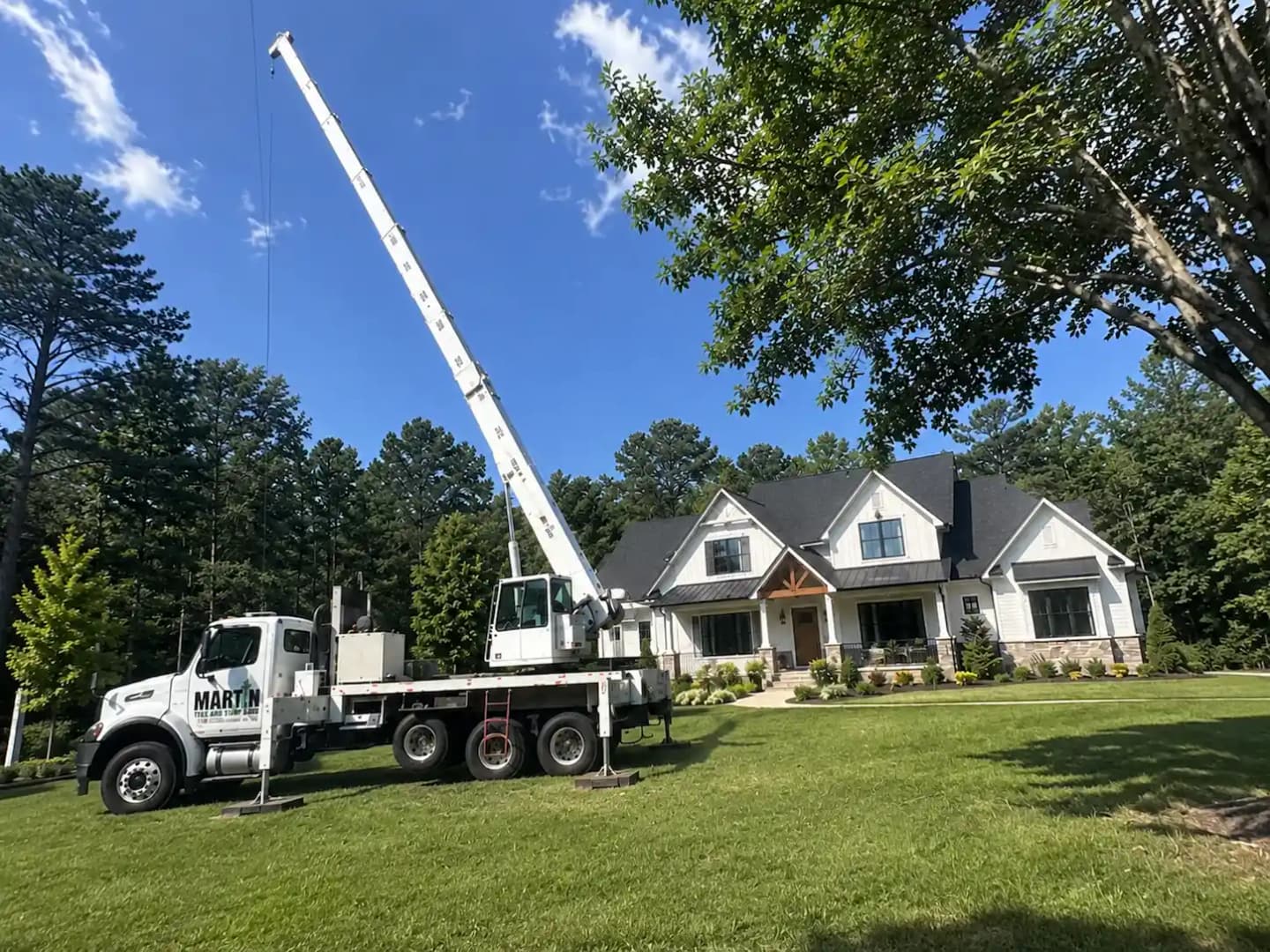 Crane-assisted tree removal over a residential structure in Upstate SC — controlled lift by Martin Tree and Turf Care crew